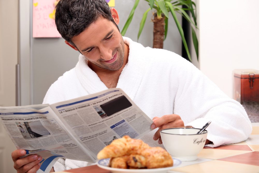 Beim Fruehstuecken einen spannenden Zeitungsartikel lesen. (Bild: auremar / Shutterstock.com)